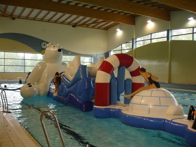 Parcours gonflable aquatique pole nord en utilisation sur une piscine avec des enfants qui jouent.