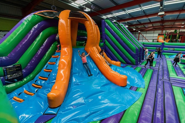 Les enfants glissent sur des toboggans gonflables géants. Sur celui-ci il y a différentes faces pour encore plus de fun.